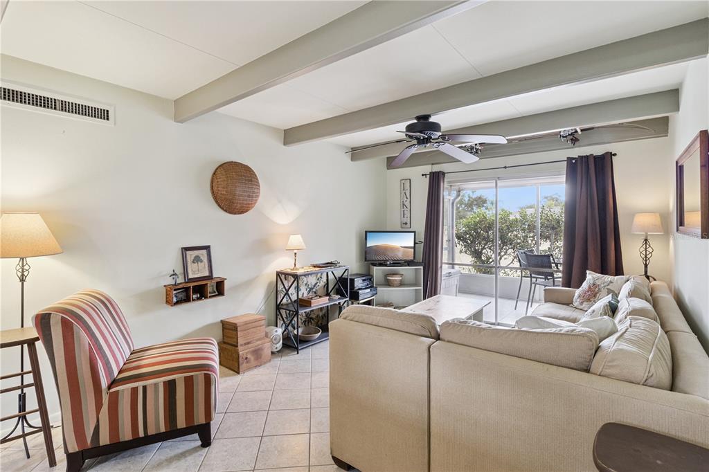 A living room features a striped armchair, a beige sectional sofa, and a sliding glass door — 1703 CLUB CIRCLE, LAKESHORE, FL
