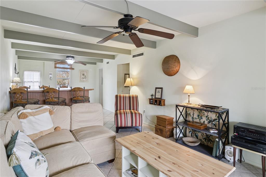 A living room features a sectional sofa, striped accent chair, wooden coffee table, and ceiling beams — 1703 CLUB CIRCLE, LAKESHORE, FL