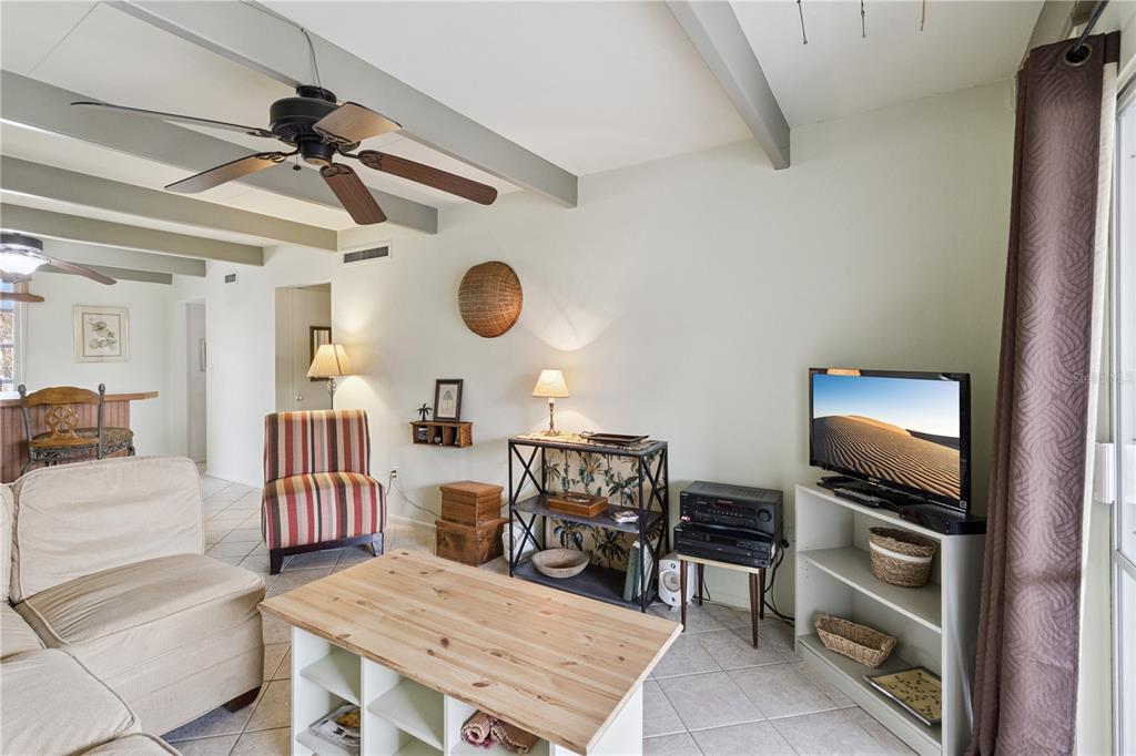 A living room features a ceiling fan, tiled floors, exposed beams, and a television stand — 1703 CLUB CIRCLE, LAKESHORE, FL