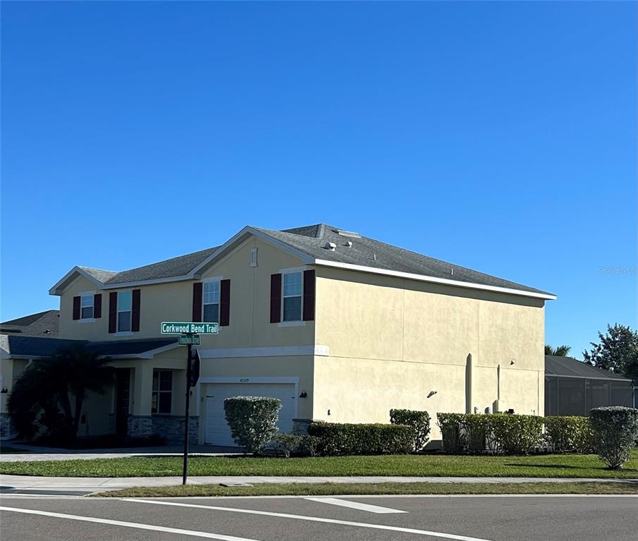 A two-story, light yellow stucco house with a garage and a street sign — 43329 TREADWAY DRIVE, PUNTA GORDA, FL