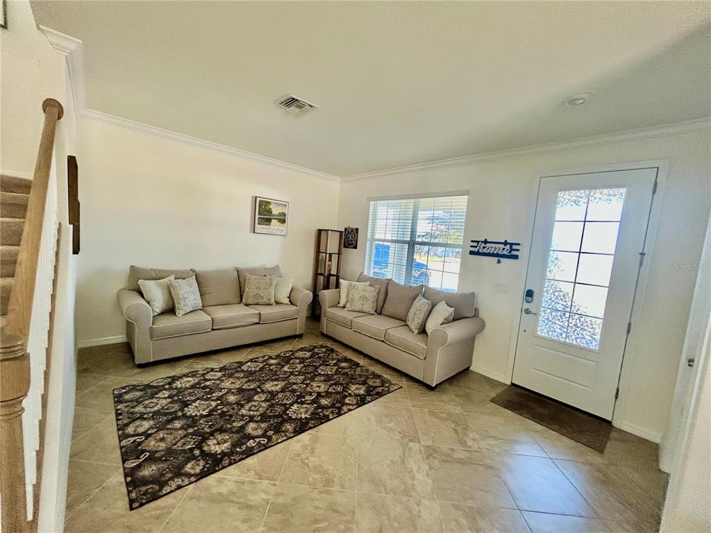 A living room features two beige sofas, a patterned area rug, and a front door — 43329 TREADWAY DRIVE, PUNTA GORDA, FL