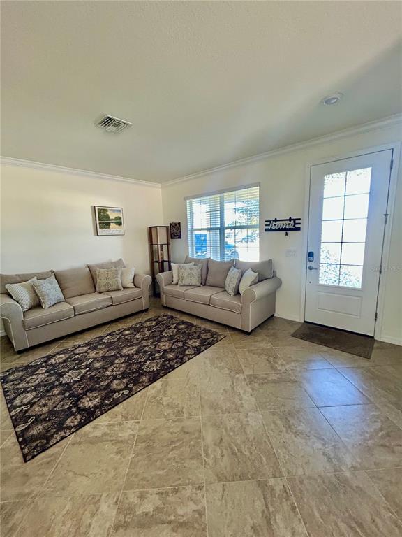 A living room features two beige sofas, a patterned area rug, and tile flooring — 43329 TREADWAY DRIVE, PUNTA GORDA, FL