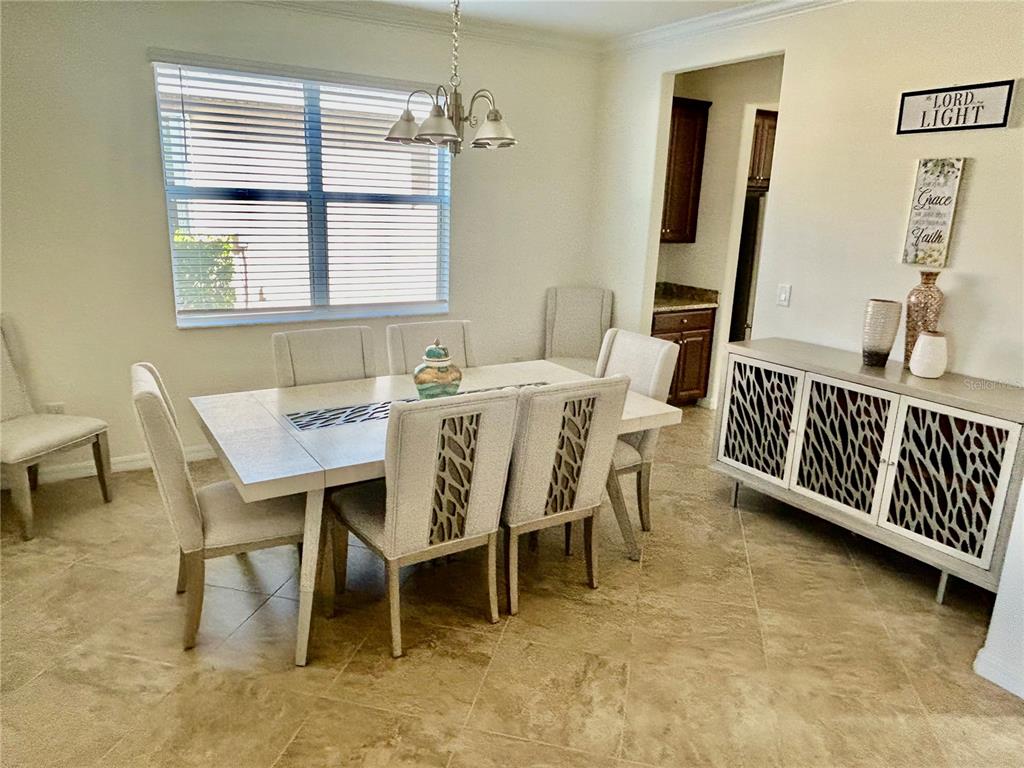A dining room features a white table, six upholstered chairs, and a patterned sideboard cabinet — 43329 TREADWAY DRIVE, PUNTA GORDA, FL