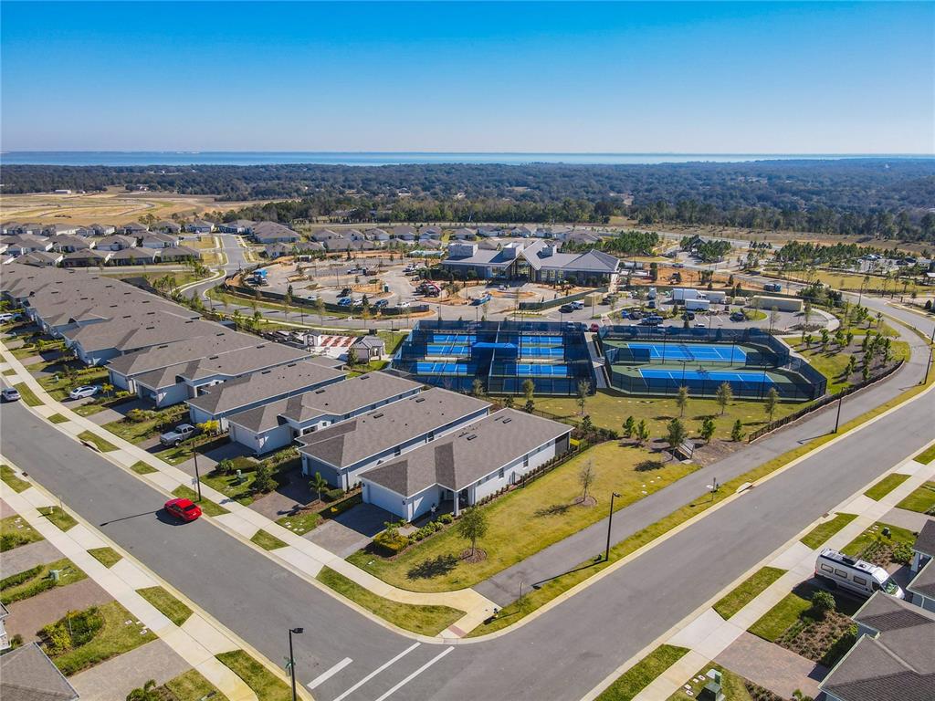 An aerial view shows a residential neighborhood with tennis courts and a community center — 2750 PURPLE MEADOW COURT, MINNEOLA, FL