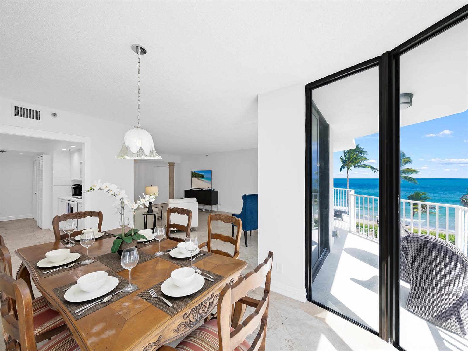 A dining area with a wooden table leads to a balcony overlooking the ocean — 2917 S Ocean Boulevard # 304, Highland Beach FL 33487, HIGHLAND BEACH, FL
