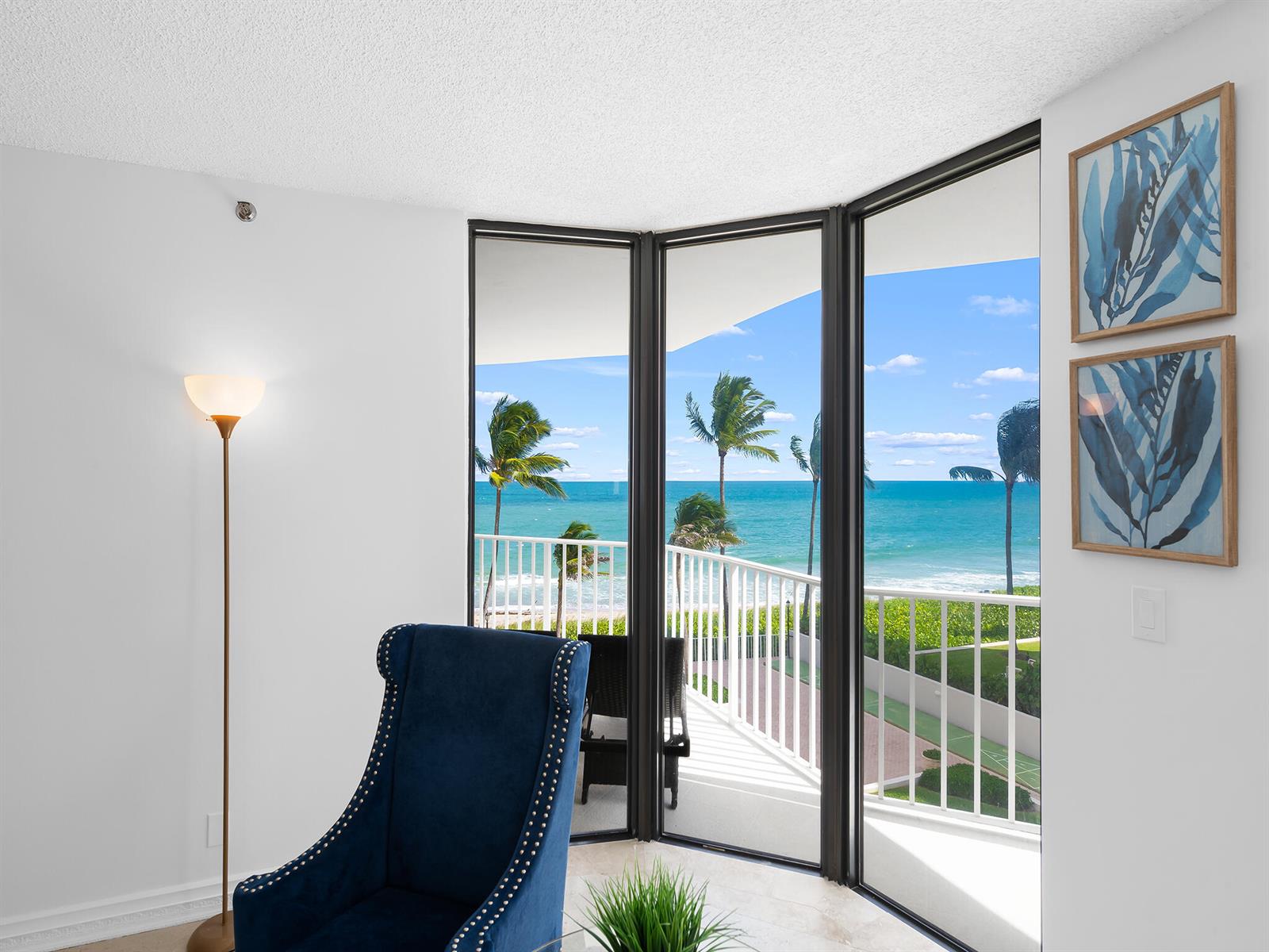 A blue armchair sits in a room with a floor-to-ceiling window overlooking the ocean — 2917 S Ocean Boulevard # 304, Highland Beach FL 33487, HIGHLAND BEACH, FL