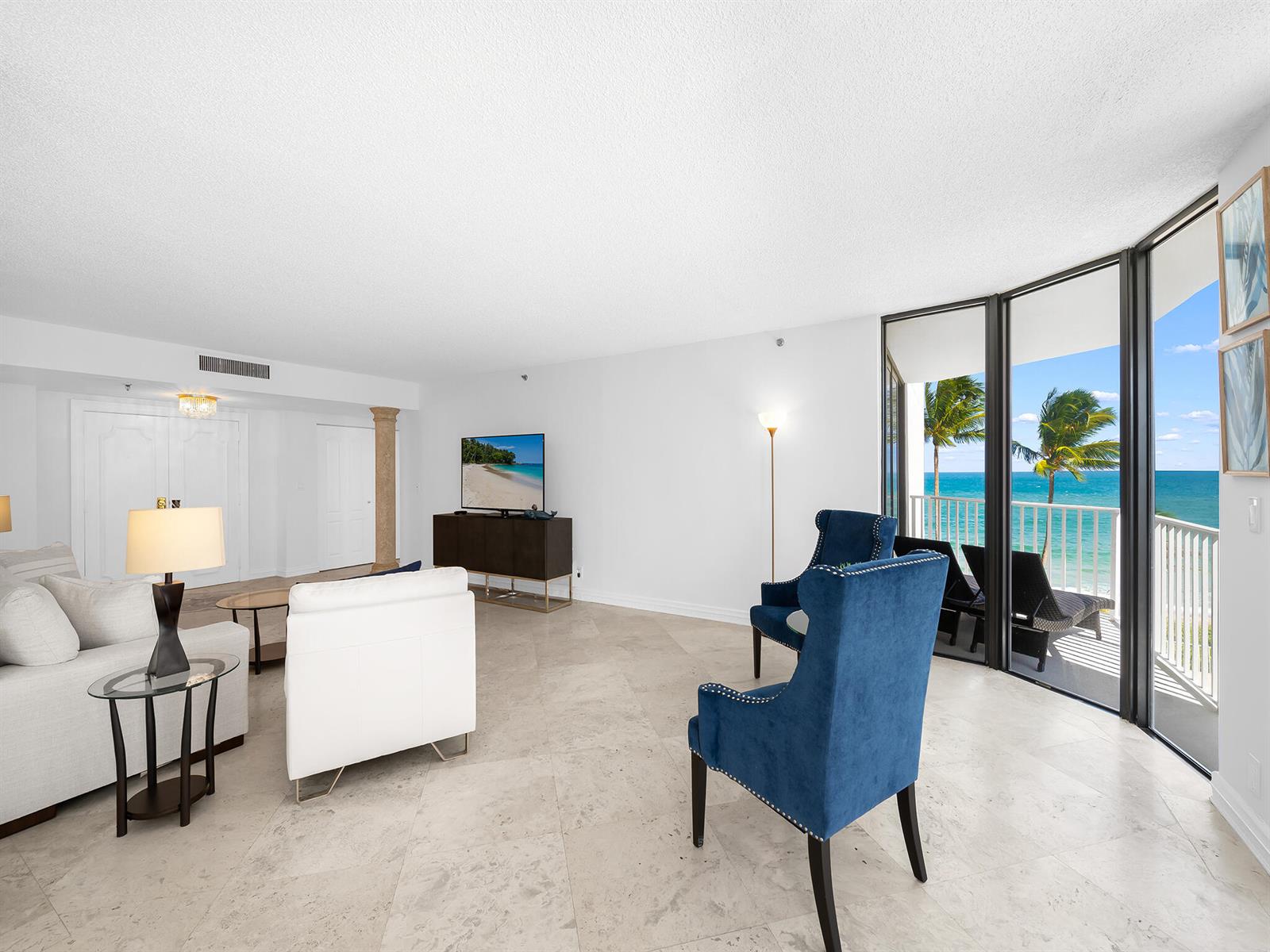 A living room with white furniture, blue armchairs, and a balcony overlooking the ocean — 2917 S Ocean Boulevard # 304, Highland Beach FL 33487, HIGHLAND BEACH, FL