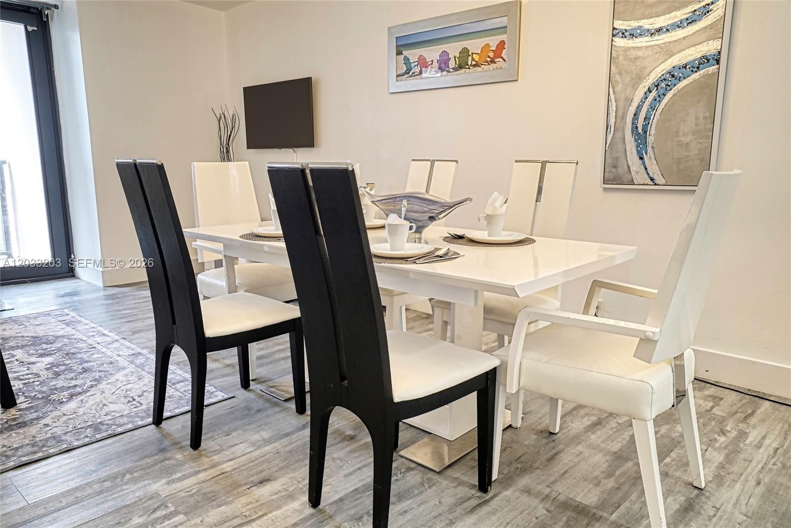 A dining room features a white table, two black chairs, and four white chairs — 5225 Collins Ave # 1204, Miami Beach FL 33140, MIAMI BEACH, FL