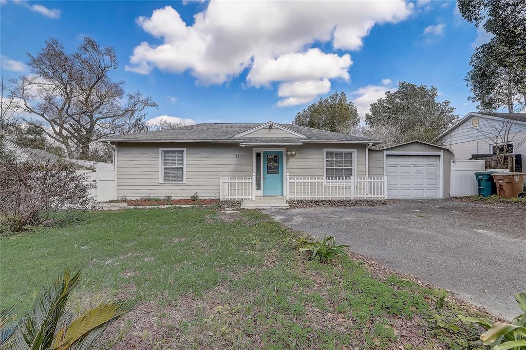 A single-story house with light siding, a blue front door, and an attached garage — 1129 NE 12TH STREET, OCALA, FL