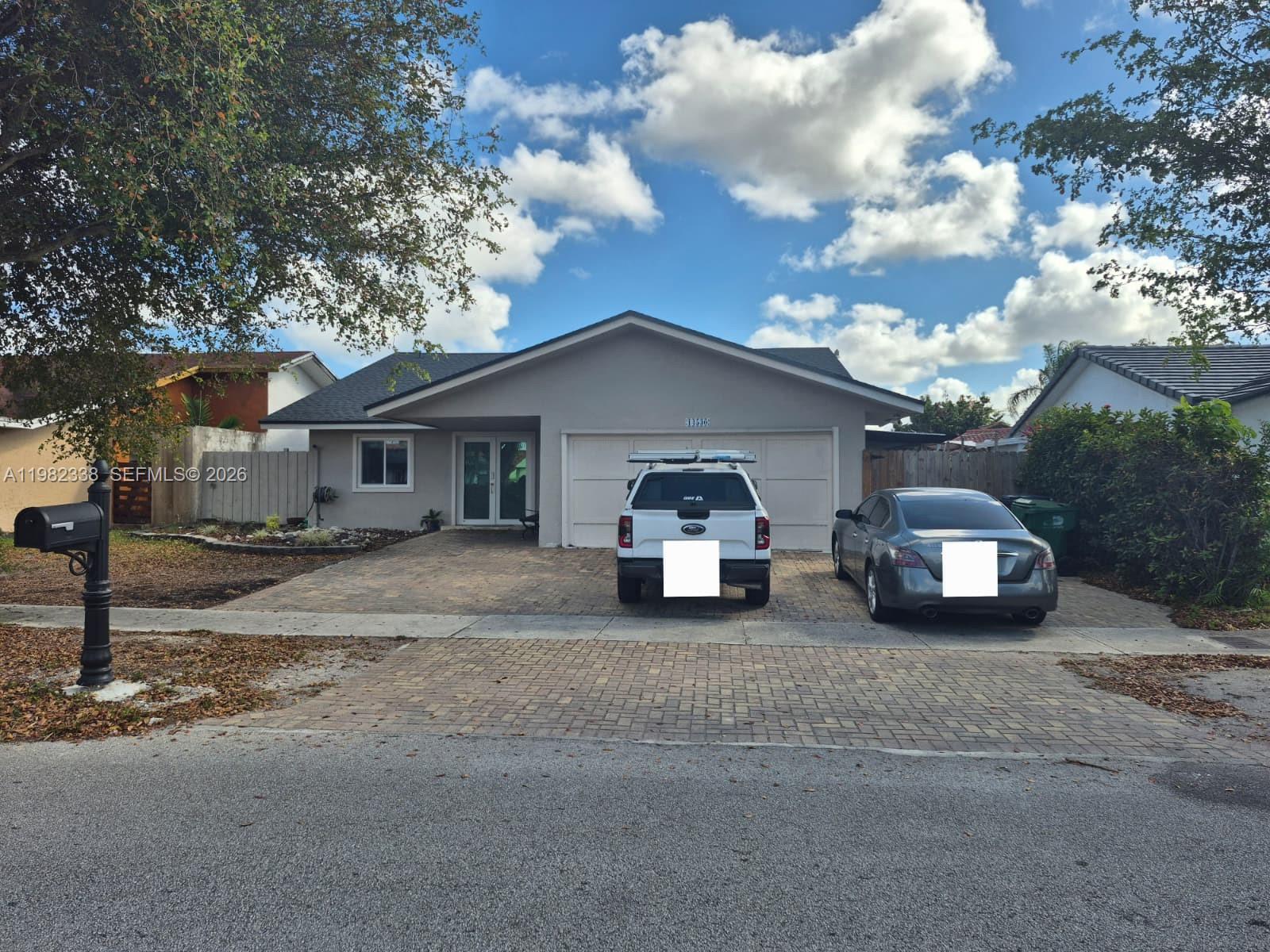 A single-story house with a gray exterior, a paved driveway, and two parked vehicles — 14530 SW 110th St, Miami FL 33186, MIAMI, FL