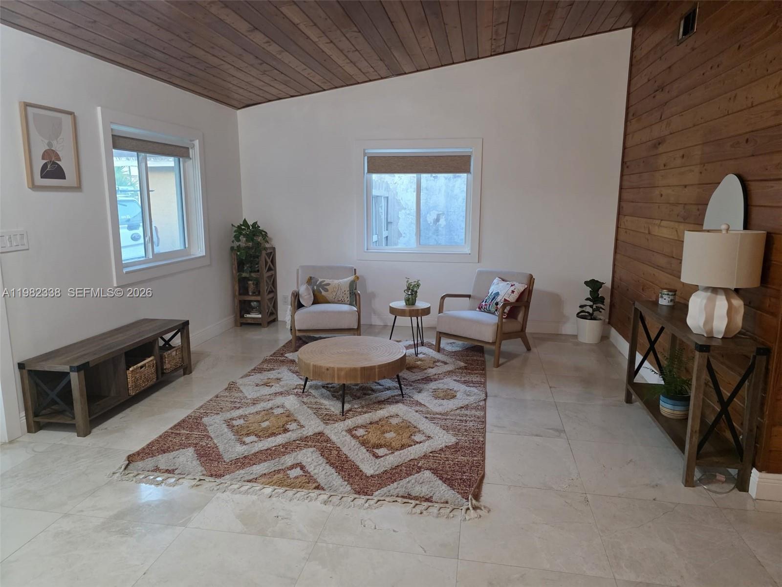 A living room features a wood-paneled ceiling, tile floors, and a geometric area rug — 14530 SW 110th St, Miami FL 33186, MIAMI, FL