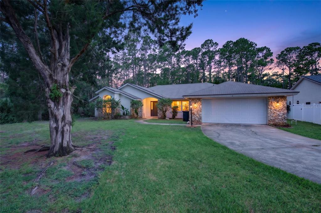A single-story house with a stone facade, two-car garage, and a large tree in front — 11 WALNUT PLACE, PALM COAST, FL