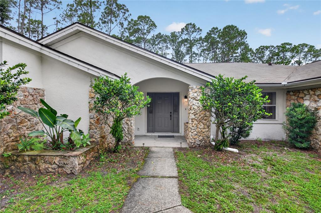 A concrete walkway leads to the front entrance of a house with stone accents — 11 WALNUT PLACE, PALM COAST, FL