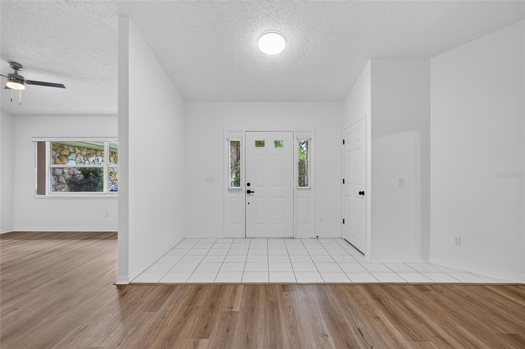 An entryway features white tile flooring, a white front door with sidelights, and wood-look flooring — 11 WALNUT PLACE, PALM COAST, FL