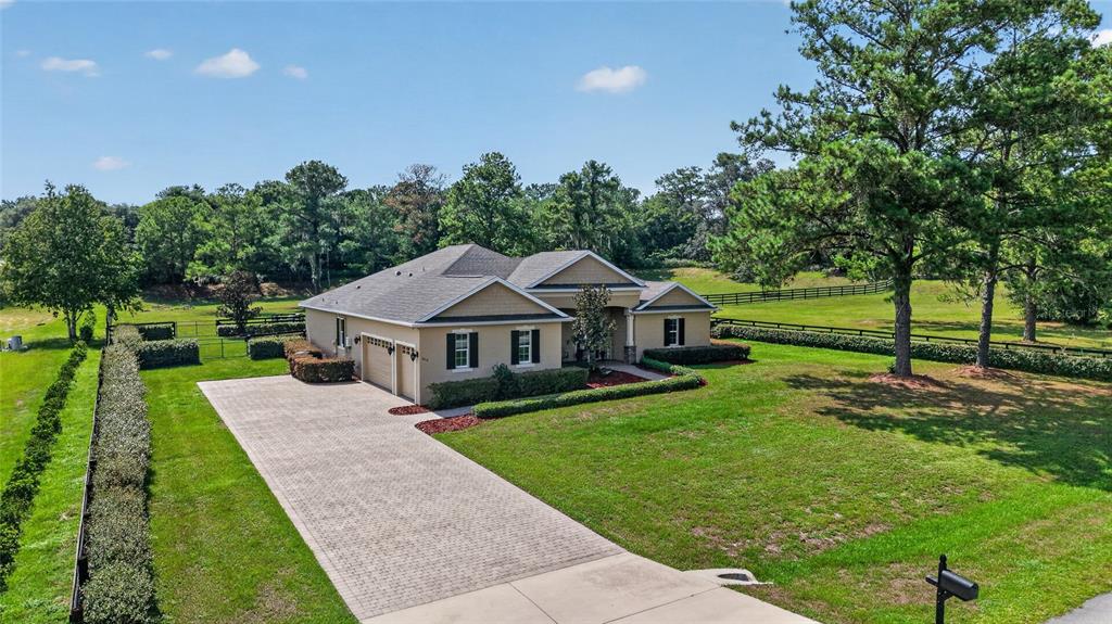An aerial view shows a single-story house with a paved driveway and surrounding green lawn — 11050 SE 37TH AVENUE ROAD, BELLEVIEW, FL