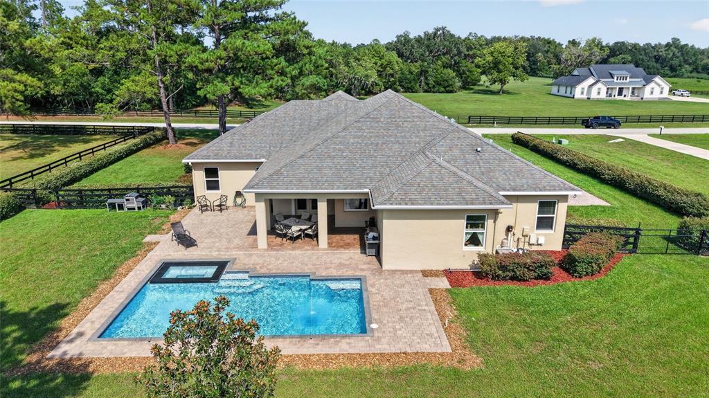 An aerial view of a house with a swimming pool, patio, and fenced backyard — 11050 SE 37TH AVENUE ROAD, BELLEVIEW, FL