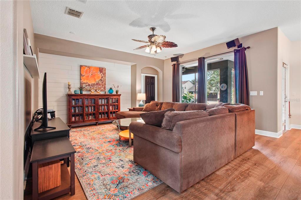 A living room features a large sectional sofa, a television on a stand, and a bookshelf — 14332 SOUTHERN RED MAPLE DRIVE, ORLANDO, FL