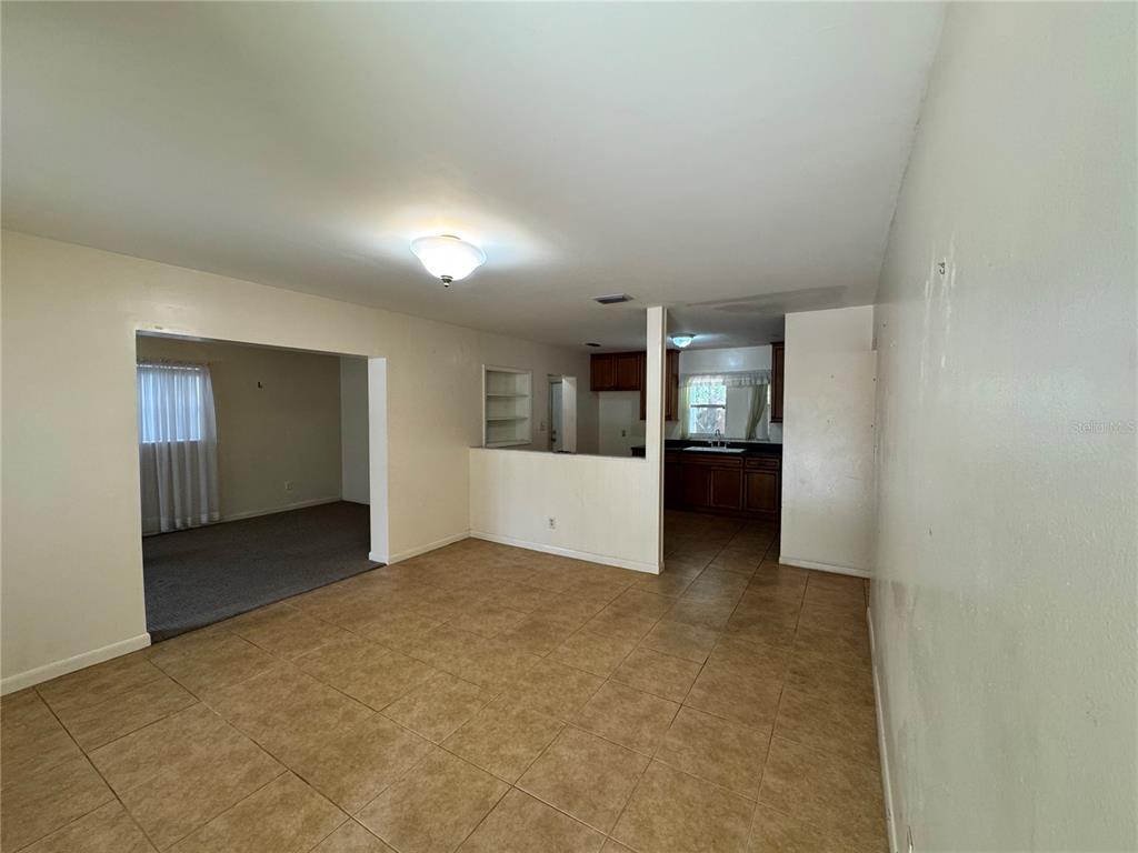 An open-concept living area with tile flooring connects to a kitchen and a carpeted room — 3608 W LEILA AVENUE, TAMPA, FL