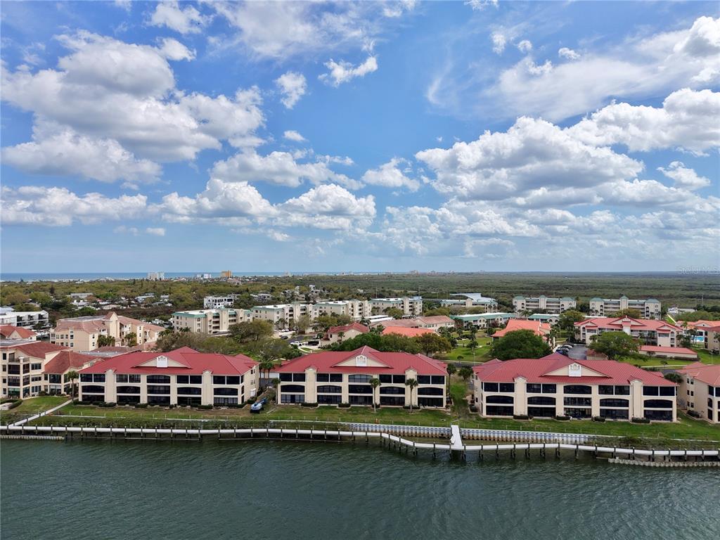 A screened-in balcony overlooks a body of water with a palm tree in the foreground — 442 BOUCHELLE DRIVE UNIT 305, NEW SMYRNA BEACH, FL