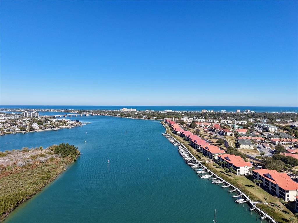 An aerial view shows a waterway lined with residential buildings and boats near the ocean — 442 BOUCHELLE DRIVE UNIT 305, NEW SMYRNA BEACH, FL