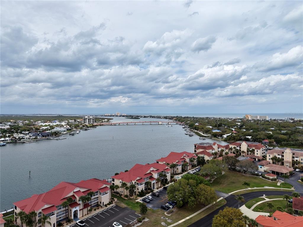 An aerial view shows a waterfront residential complex with red roofs near a bridge — 442 BOUCHELLE DRIVE UNIT 305, NEW SMYRNA BEACH, FL
