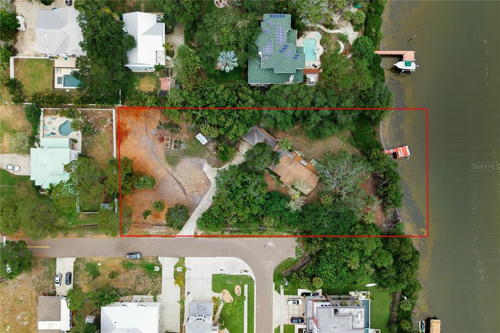 An aerial view shows a waterfront property with a house, trees, and a private dock — 700 DELAWARE AVENUE, PALM HARBOR, FL