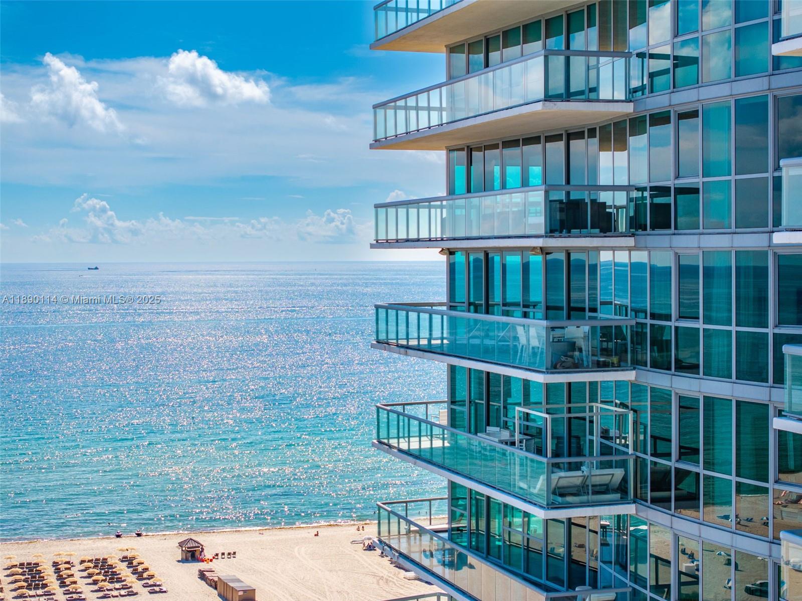 An exterior view of a high-rise building with glass balconies overlooking a sandy beach — 101 20th St # 2007, Miami Beach FL 33139, MIAMI BEACH, FL