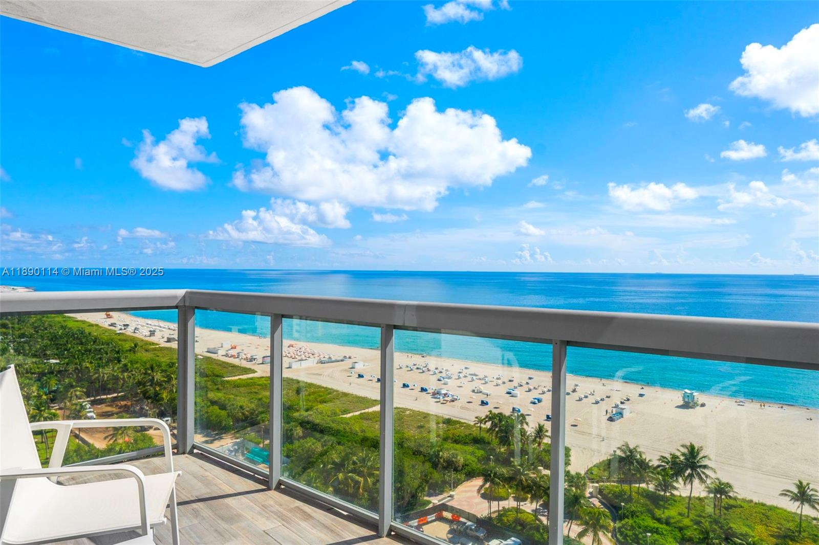 A high-rise balcony overlooks a sandy beach, palm trees, and the ocean under a blue sky — 101 20th St # 2007, Miami Beach FL 33139, MIAMI BEACH, FL