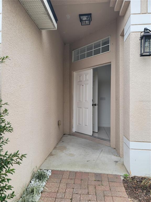 An exterior view of a home entrance with a white door and a brick walkway — 601 ASTOR DRIVE, HAINES CITY, FL