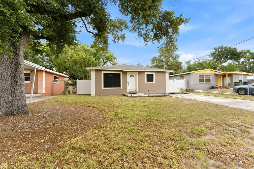 A single-story tan house with a front porch and a large tree in the yard — 3708 E IDLEWILD AVENUE, TAMPA, FL