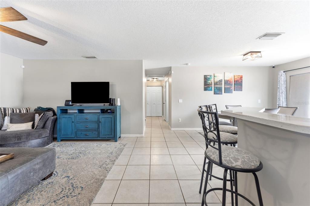 A living room and kitchen area with tile flooring, a blue console, and bar seating — 3708 E IDLEWILD AVENUE, TAMPA, FL
