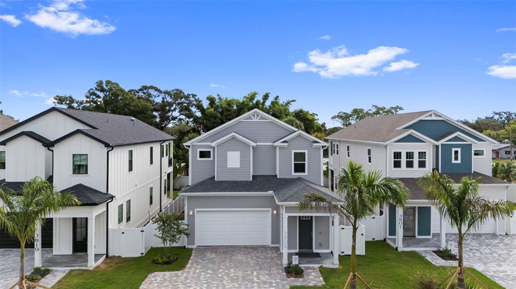 Three modern two-story houses with paved driveways stand side-by-side under a blue sky — 3809 71ST STREET N, ST PETERSBURG, FL