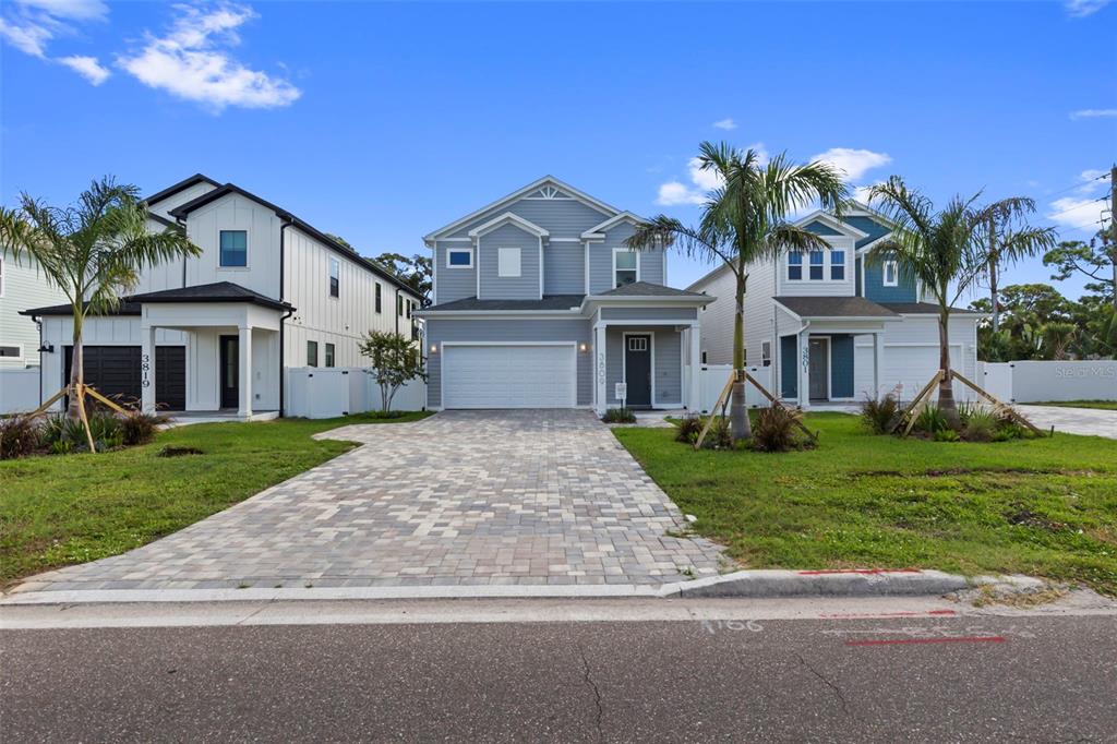 Three modern two-story houses with paved driveways stand side-by-side under a clear blue sky — 3809 71ST STREET N, ST PETERSBURG, FL