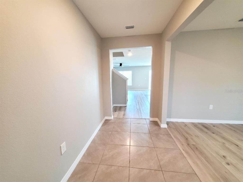 A tiled entryway leads to a living area with wood-look flooring and a staircase — 1014 GOLDEN SHINER AVENUE, RUSKIN, FL