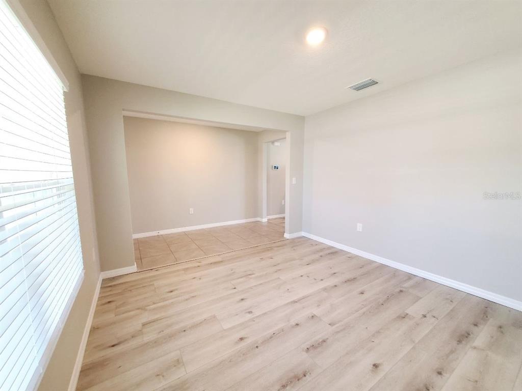 A room with light wood-look flooring and a tiled area visible through an opening — 1014 GOLDEN SHINER AVENUE, RUSKIN, FL
