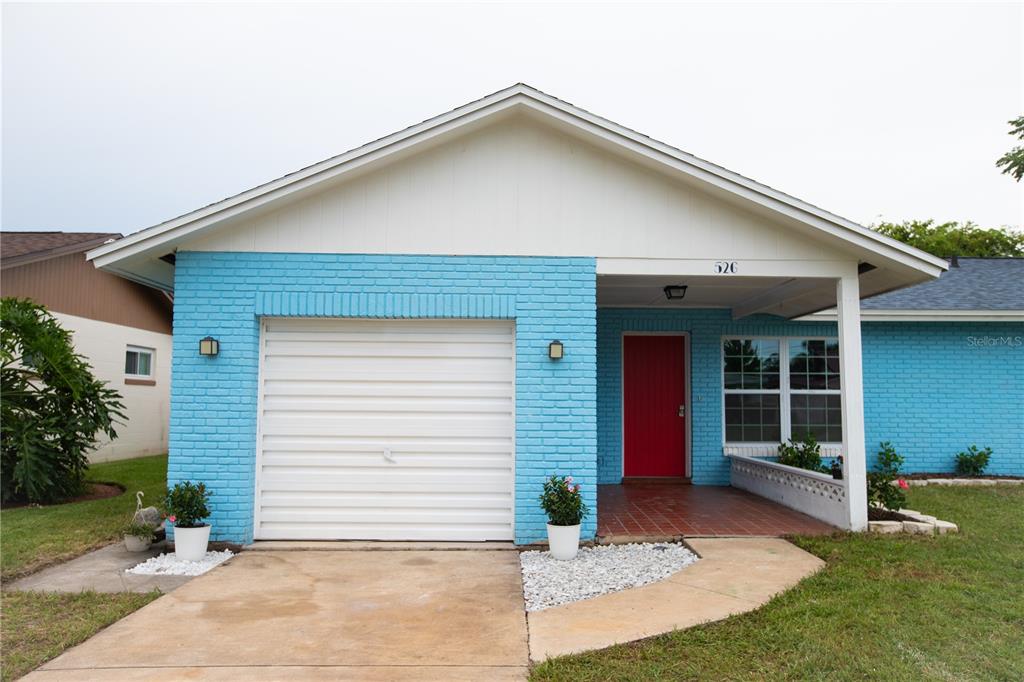 A single-story house with blue painted brick, a white garage door, and a red front door — 526 DORSET CIRCLE, SOUTH DAYTONA, FL