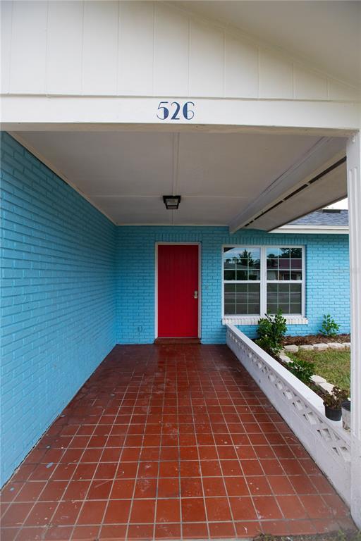 A covered porch with red tile flooring leads to a bright red front door — 526 DORSET CIRCLE, SOUTH DAYTONA, FL