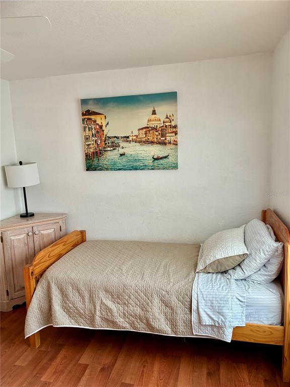A bedroom features a wooden bed frame, a corner cabinet with a lamp, and wall art — 4122 RESIDENCE DRIVE UNIT 120, FORT MYERS, FL