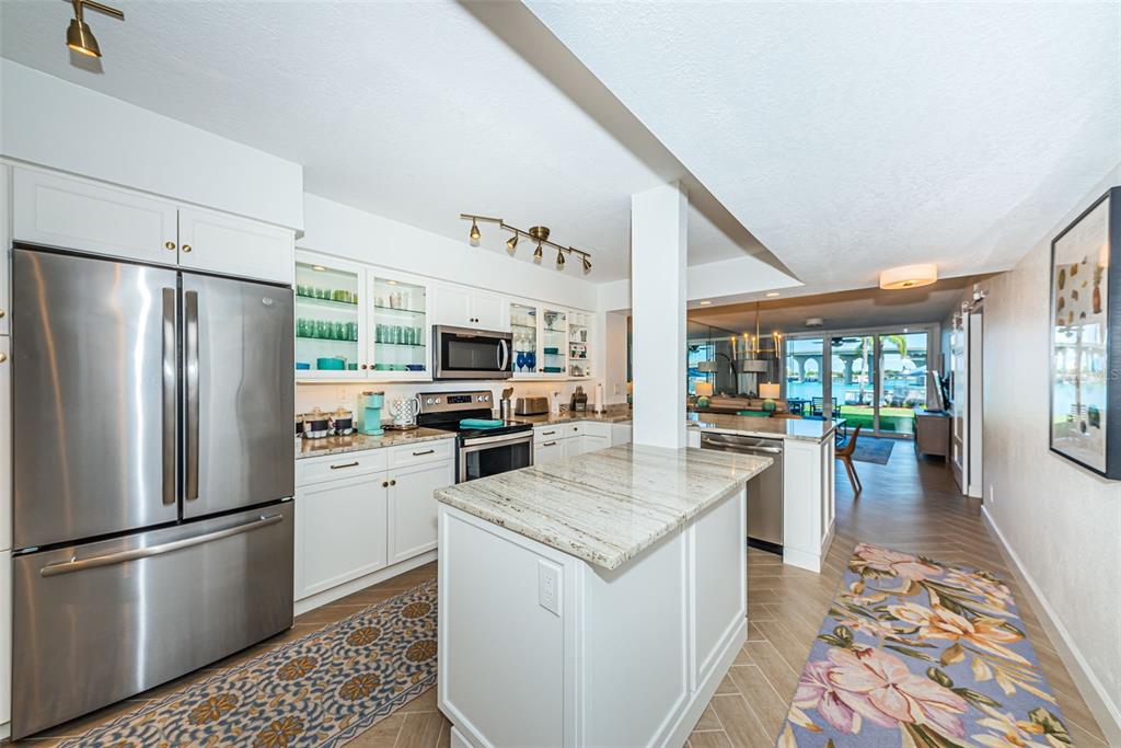 A white kitchen with stainless steel appliances, granite countertops, and a view of the water — 5901 BAHIA DEL MAR CIRCLE UNIT 122, ST PETERSBURG, FL