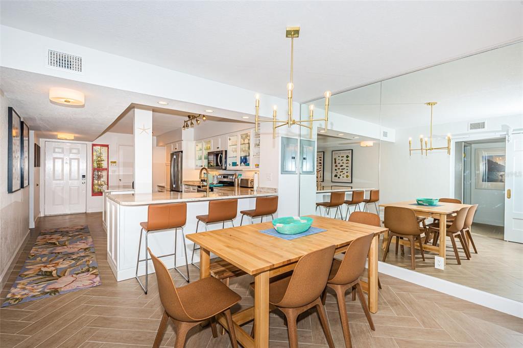 A dining area with a wooden table and chairs sits next to a kitchen island — 5901 BAHIA DEL MAR CIRCLE UNIT 122, ST PETERSBURG, FL