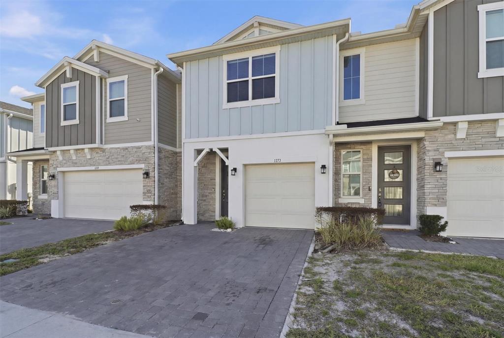 A row of modern townhomes features stone veneer, light-colored siding, and attached garages — 1375 CAPTIVA COVE, SANFORD, FL