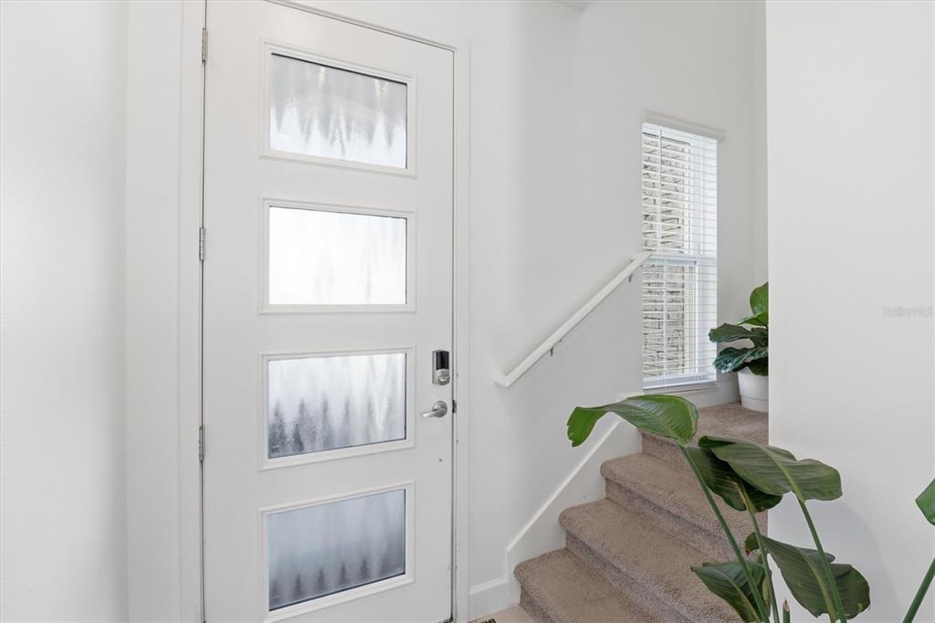 A white front door with four glass panels sits beside carpeted stairs and a window — 1375 CAPTIVA COVE, SANFORD, FL