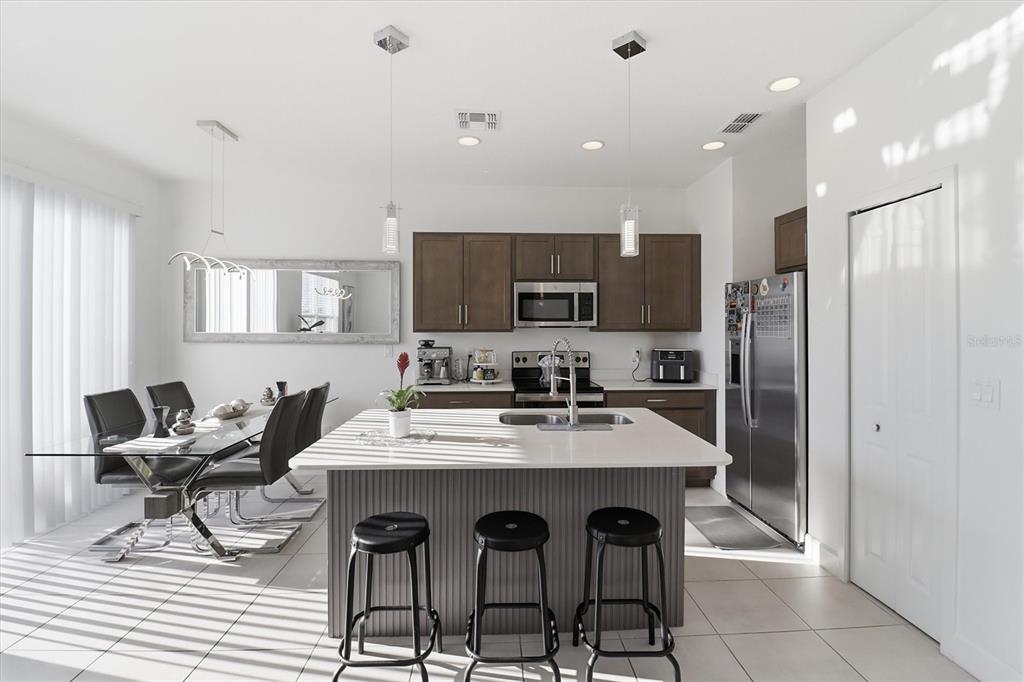 A kitchen with dark wood cabinets, a white island, and an adjacent dining area — 1375 CAPTIVA COVE, SANFORD, FL