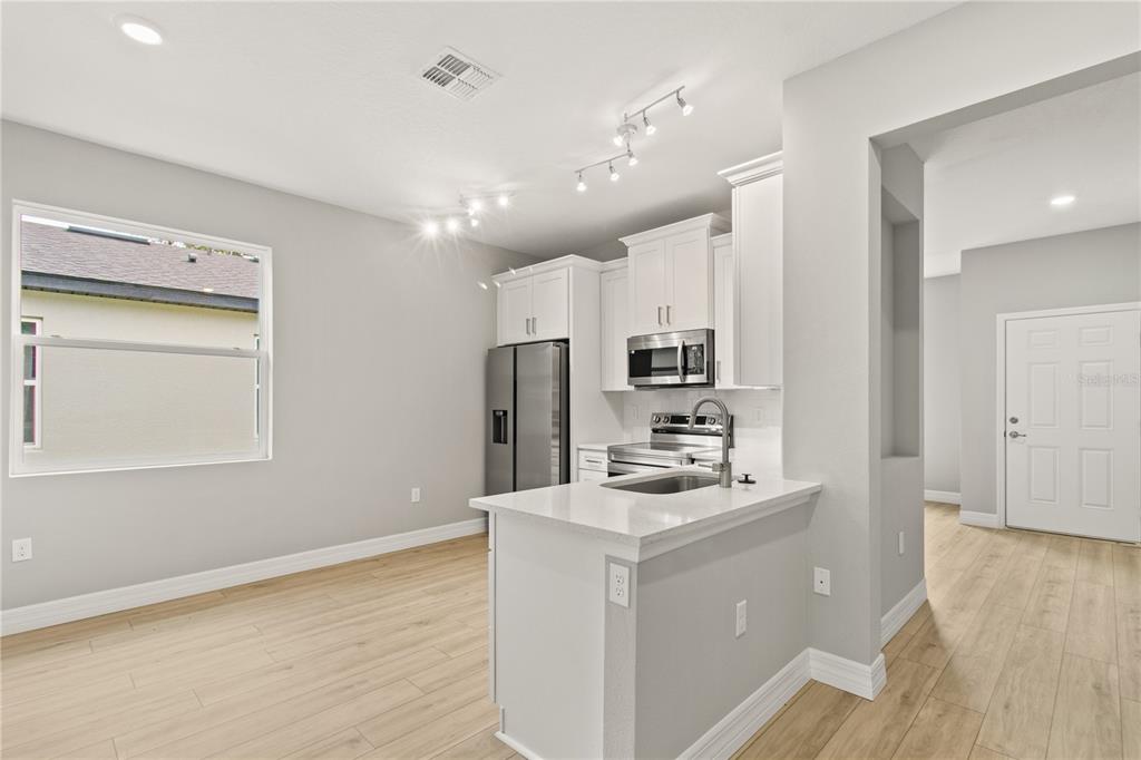 A kitchen with white cabinets, stainless steel appliances, and light wood-look flooring — 3647 SUMMER HAVEN LANE, APOPKA, FL