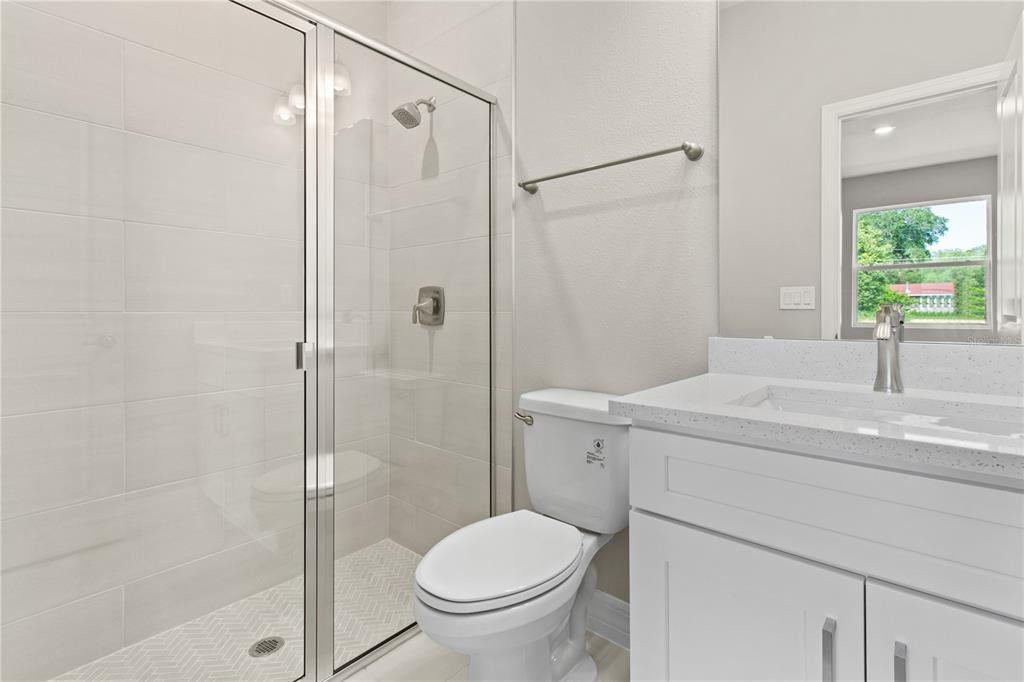 A bathroom features a glass-enclosed shower, a white toilet, and a vanity with a countertop — 3647 SUMMER HAVEN LANE, APOPKA, FL