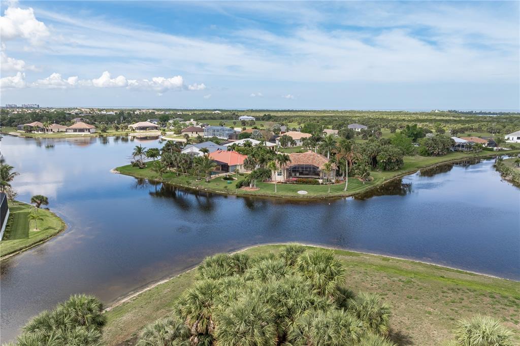An aerial view shows houses situated on a peninsula surrounded by a large lake — 16396 NOGALES COURT, PUNTA GORDA, FL