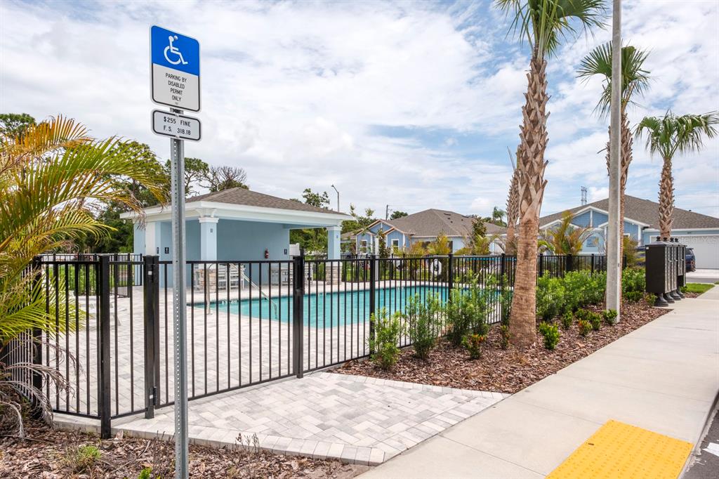 A swimming pool with a covered patio area is enclosed by a black metal fence — 2580 MARIO WAY, CLEARWATER, FL