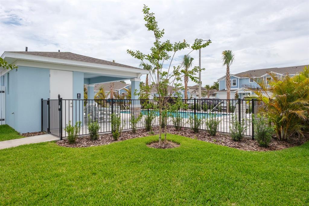 A fenced community pool area with a covered patio and a small tree in the foreground — 2580 MARIO WAY, CLEARWATER, FL