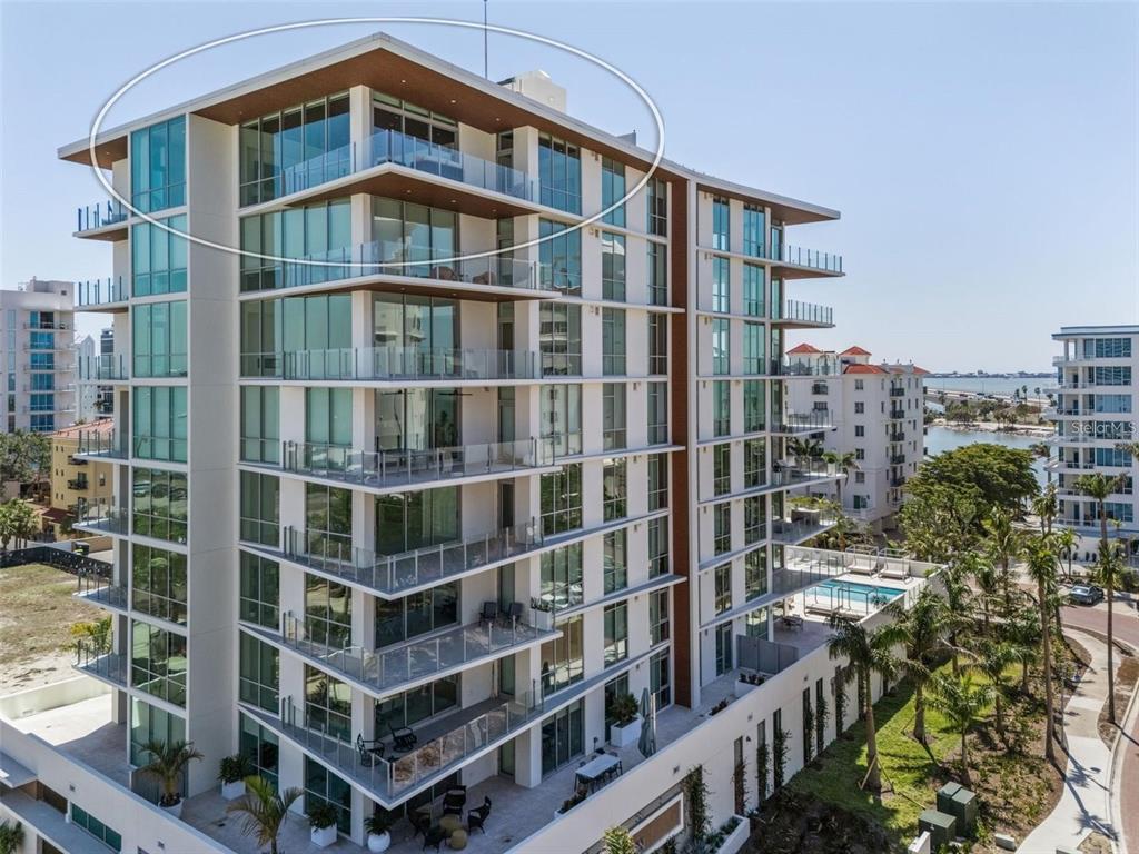 An exterior view of a modern high-rise condominium building with glass balconies and wood-paneled ceilings — 111 GOLDEN GATE POINT UNIT 802PH, SARASOTA, FL