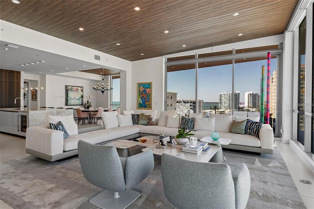 A modern living room features a large sectional sofa, two armchairs, and floor-to-ceiling windows — 111 GOLDEN GATE POINT UNIT 802PH, SARASOTA, FL